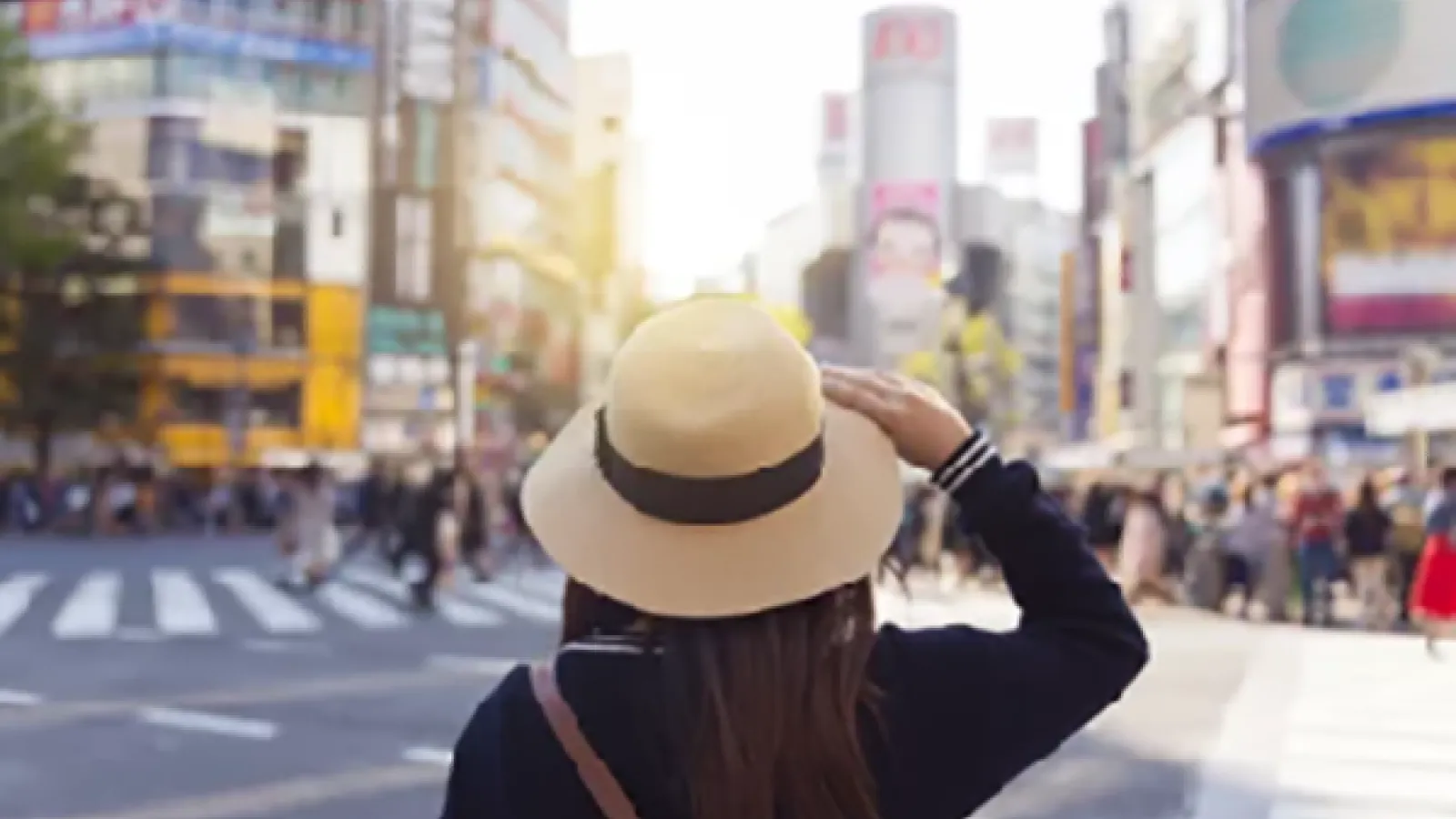 girl wearing a straw hat looking out at the Shibuya Scramble Crossing