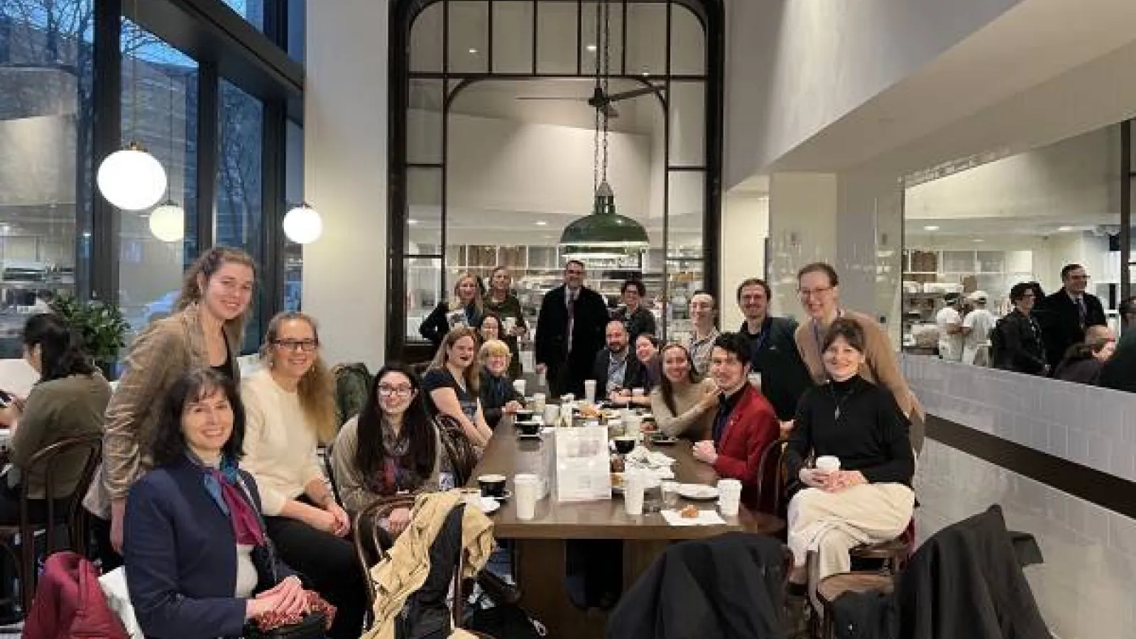 A group photo of CSEEES students, alumni, faculty and staff in a coffee shop