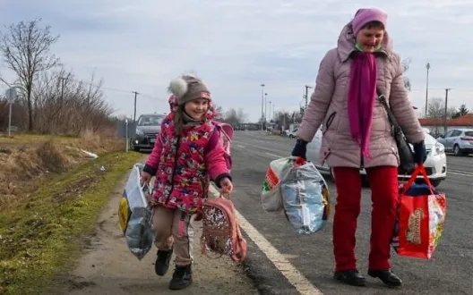 A Ukrainian mother walks with her daughter along the road from the Hungarian-Ukrainian border crossing near Beregsurany, Hungary
